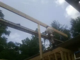 Carpenter setting a ridge beam over a new addition frame — Ice Dam Removal by Roofing Brothers in Prineville