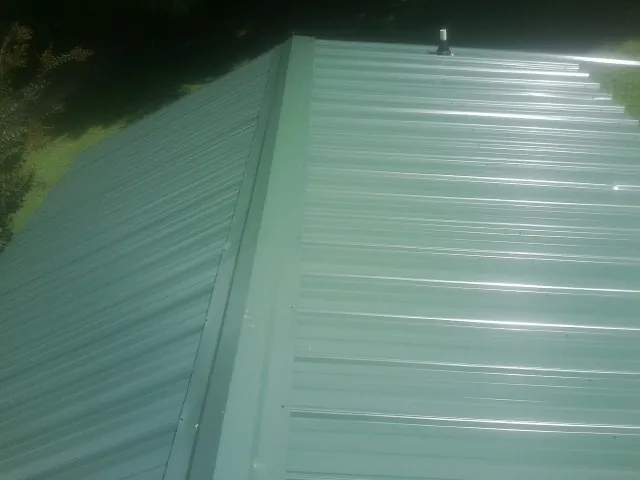 New green metal panels meeting at the ridge of a roof — Flat Roof Repair work by our crew in Prineville