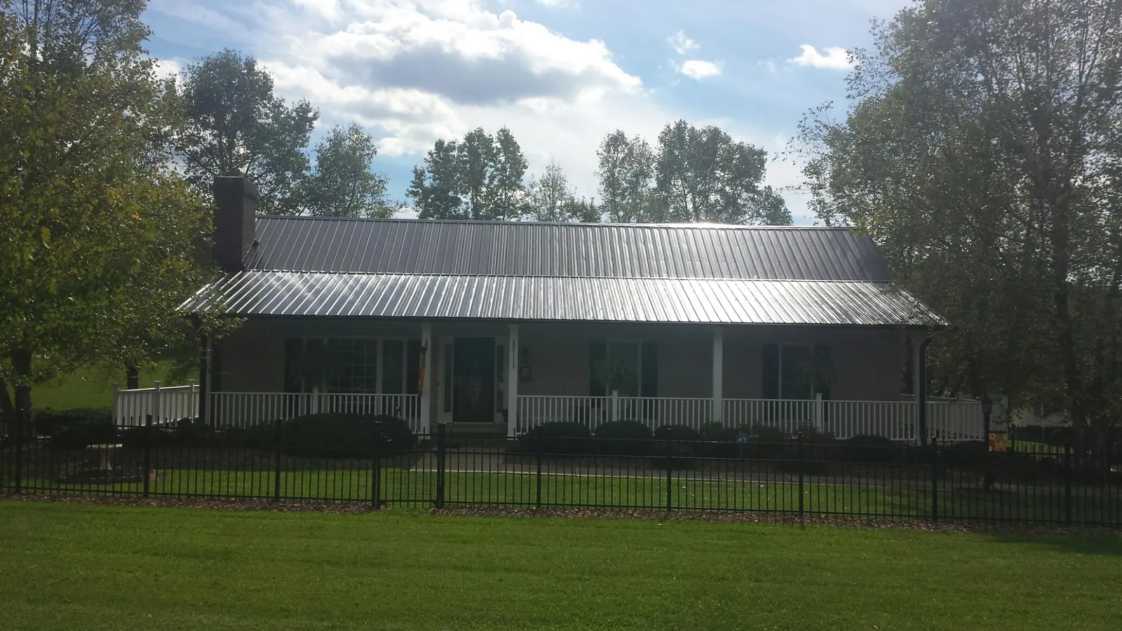Gray metal roof on a brick ranch with a full width front porch — Gutter Guard Installation work by our crew in Prineville