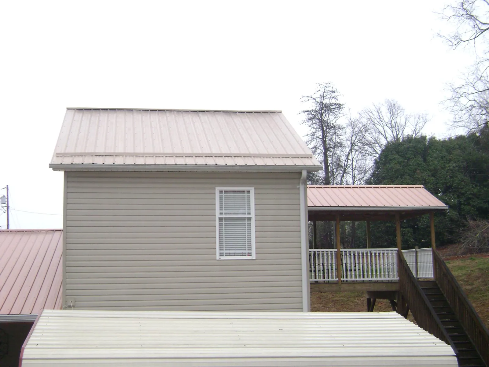 Tan metal roofs on a two story addition and attached porch, from a Roof Replacement job in Prineville