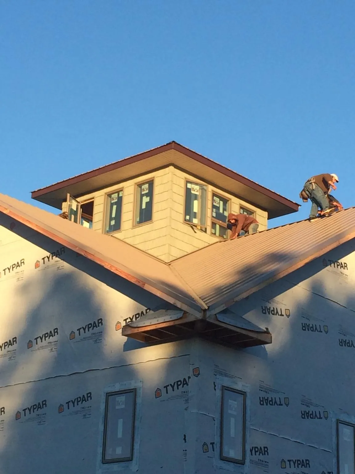 Roofers working around a rooftop cupola on a new metal roof at sunset — Roof Waterproofing in Prineville by Roofing Brothers